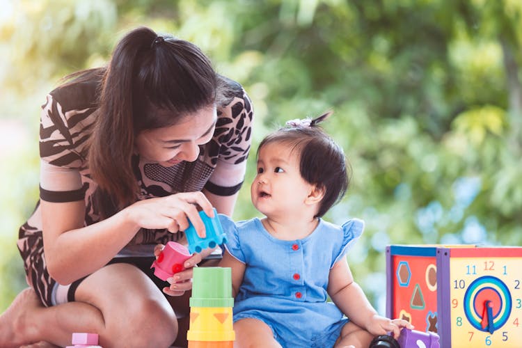 young woman mother playing with baby girl educational toys